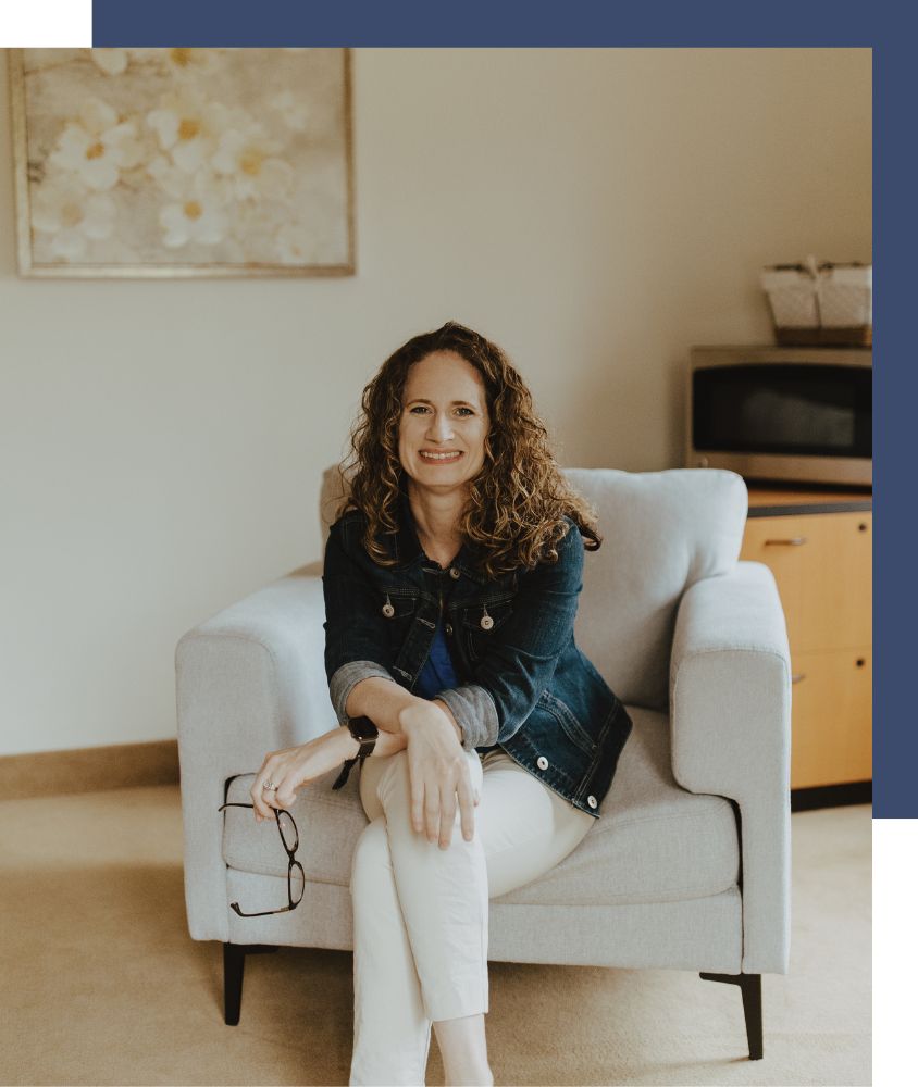 Therapist sitting in a white arm chair with glasses in hand in Cleveland Ohio