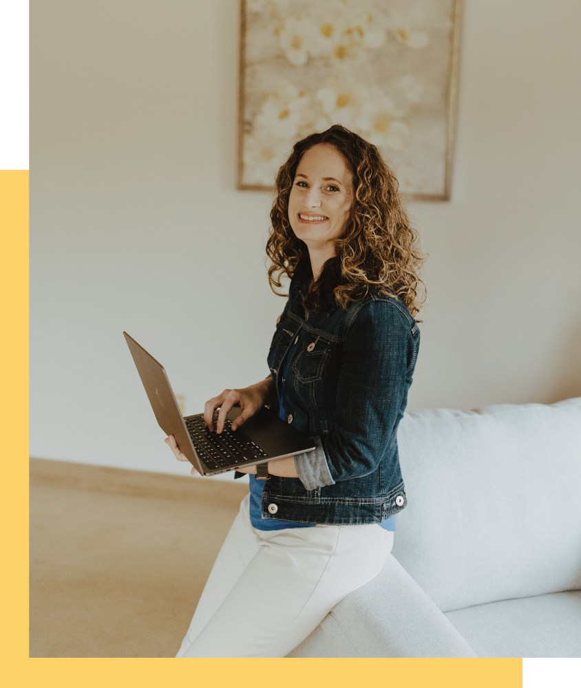 Melissa Goldsmith, PTSD therapist, leaning on a white chair with a laptop in her hands smiling